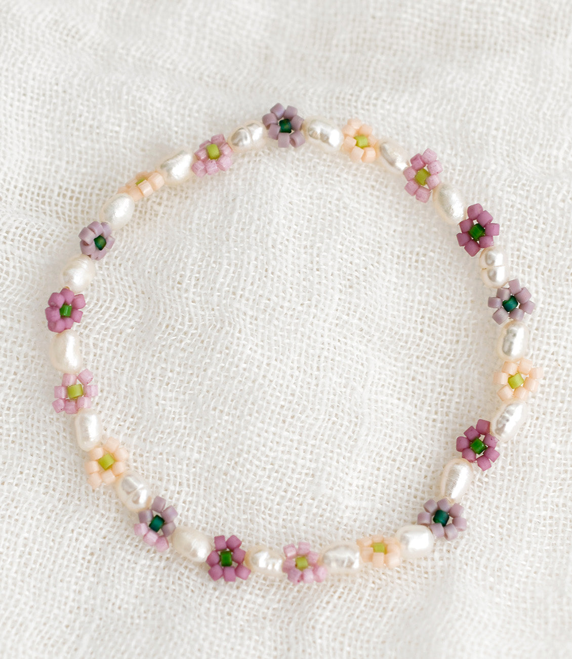 A beaded bracelet with white pearls and multicolor flowers.