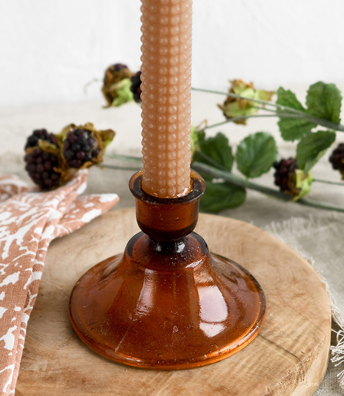 An amber colored glass taper holder with hobnail textured candle.