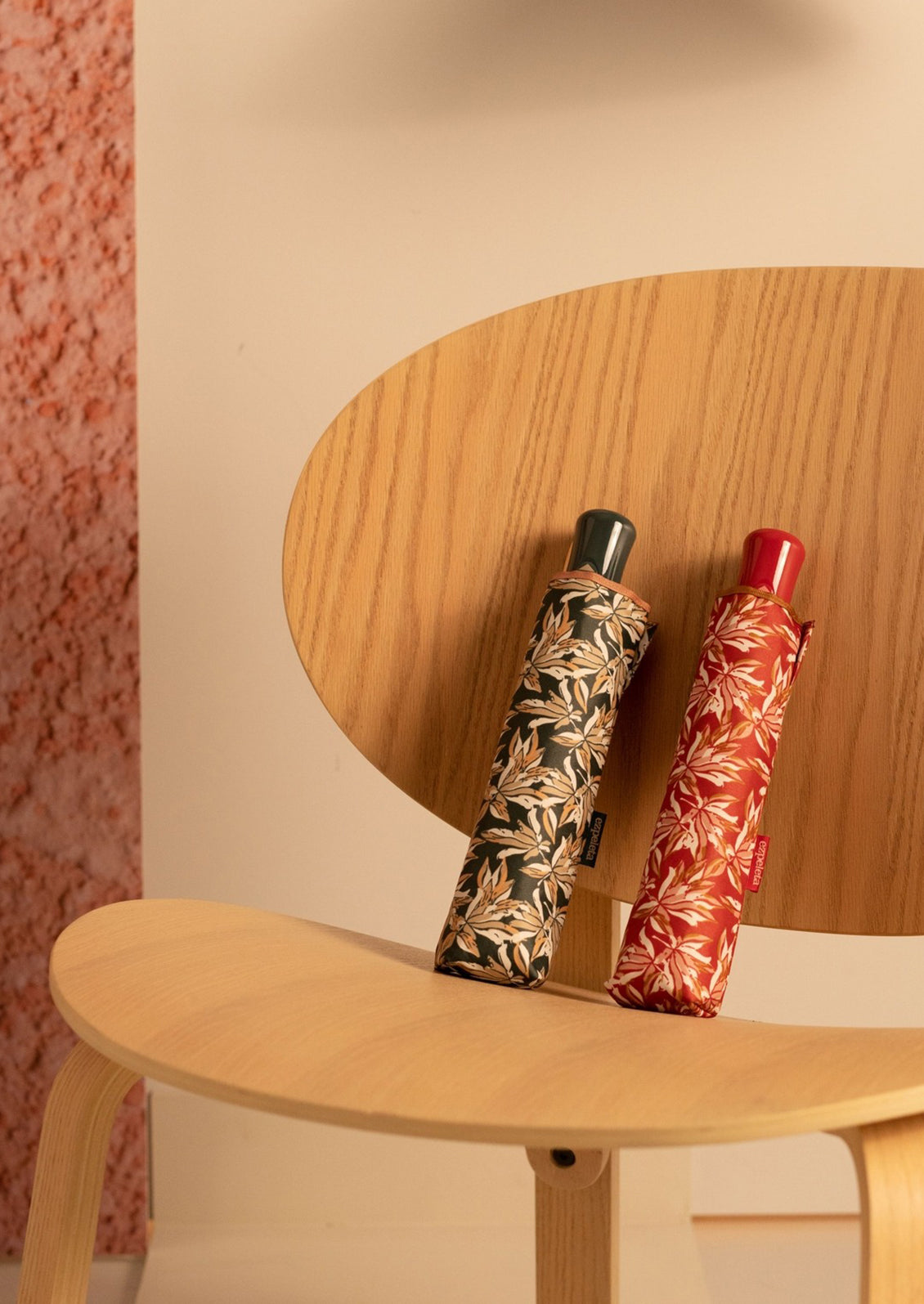 Red and black floral print umbrellas displayed on a chair.