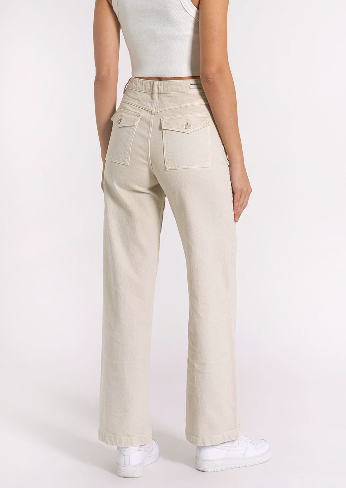 Cream colored denim jeans with high rise and back patch pocket with button flap closure.