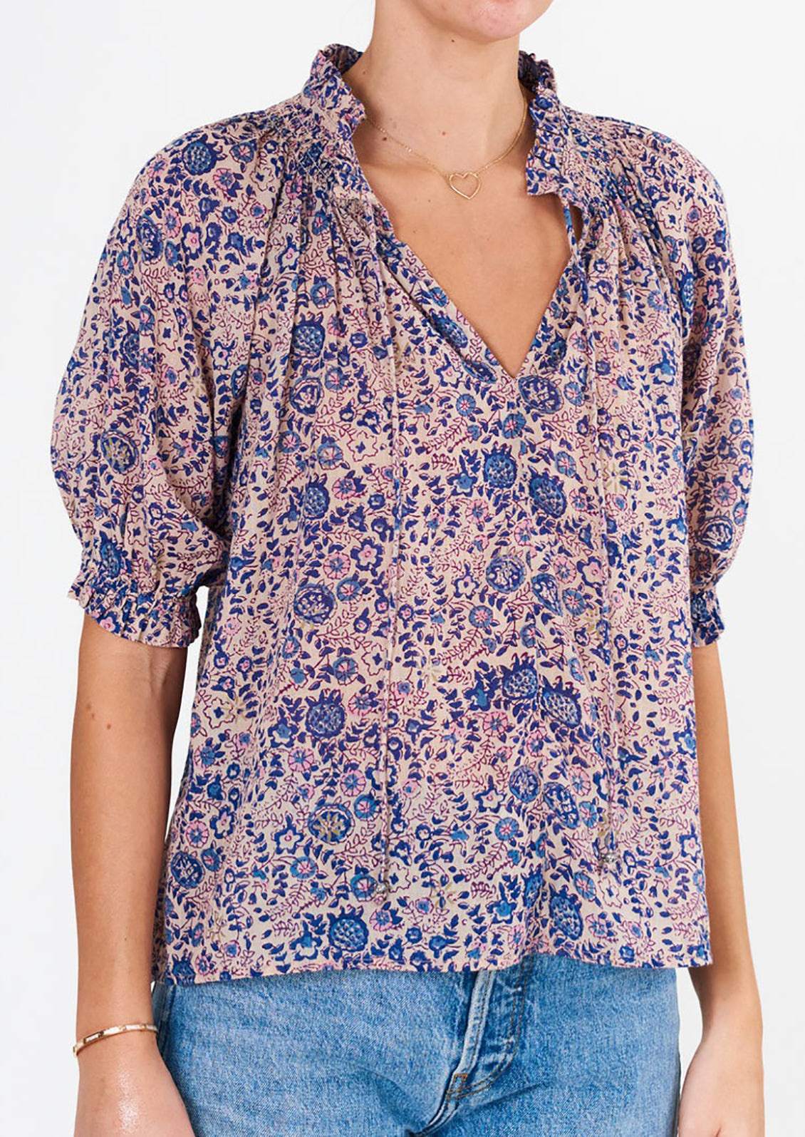 A woman wearing a floral block printed shirt with short sleeves.