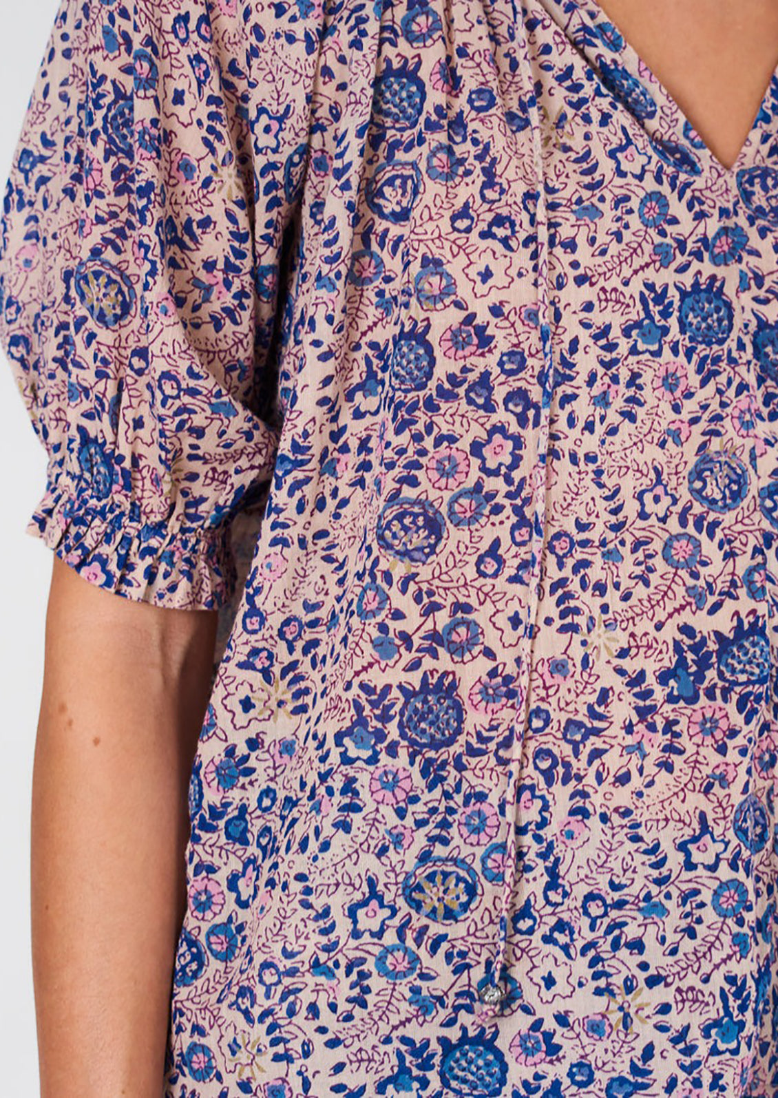 A woman wearing a floral block printed shirt with short sleeves.