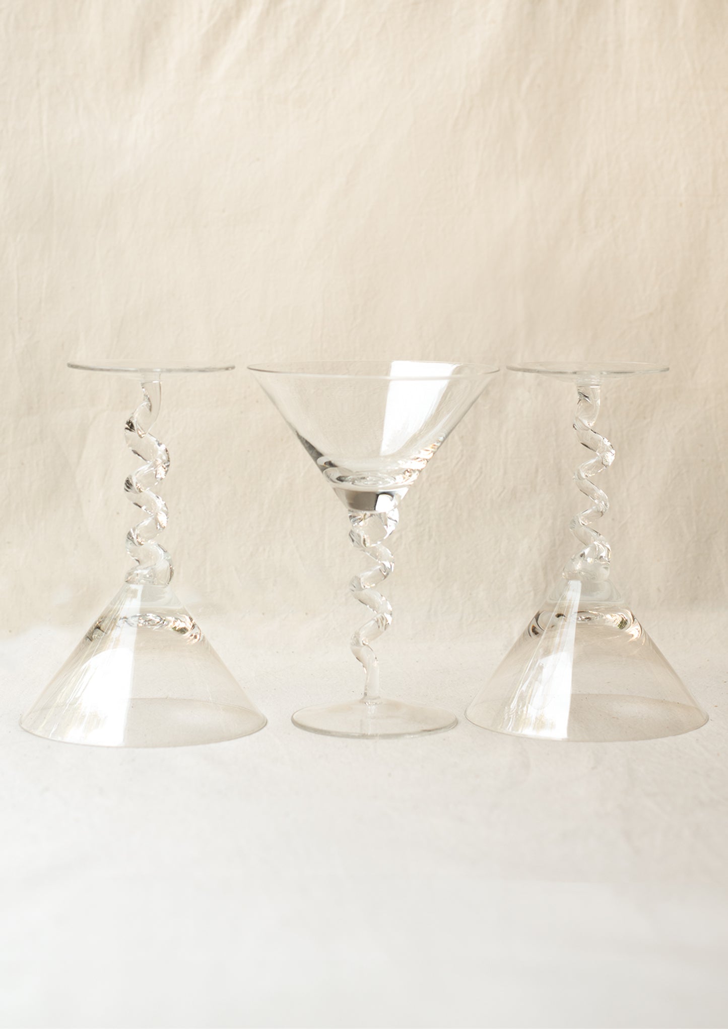 A clear martini glass with twisted stem shape.