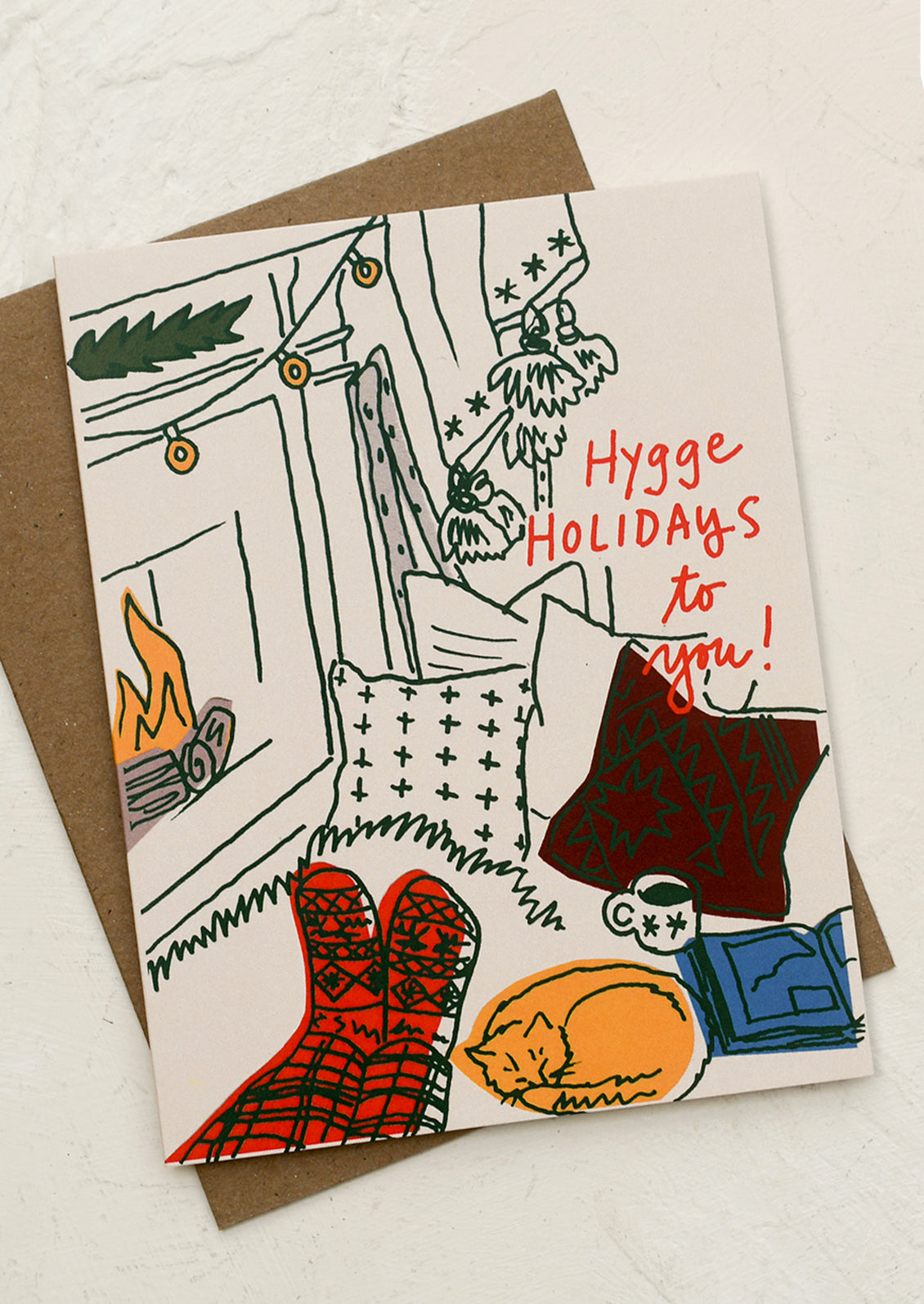 A set of cards with illustration of person sitting next to fireplace, text reads "Hygge Holidays To You!".