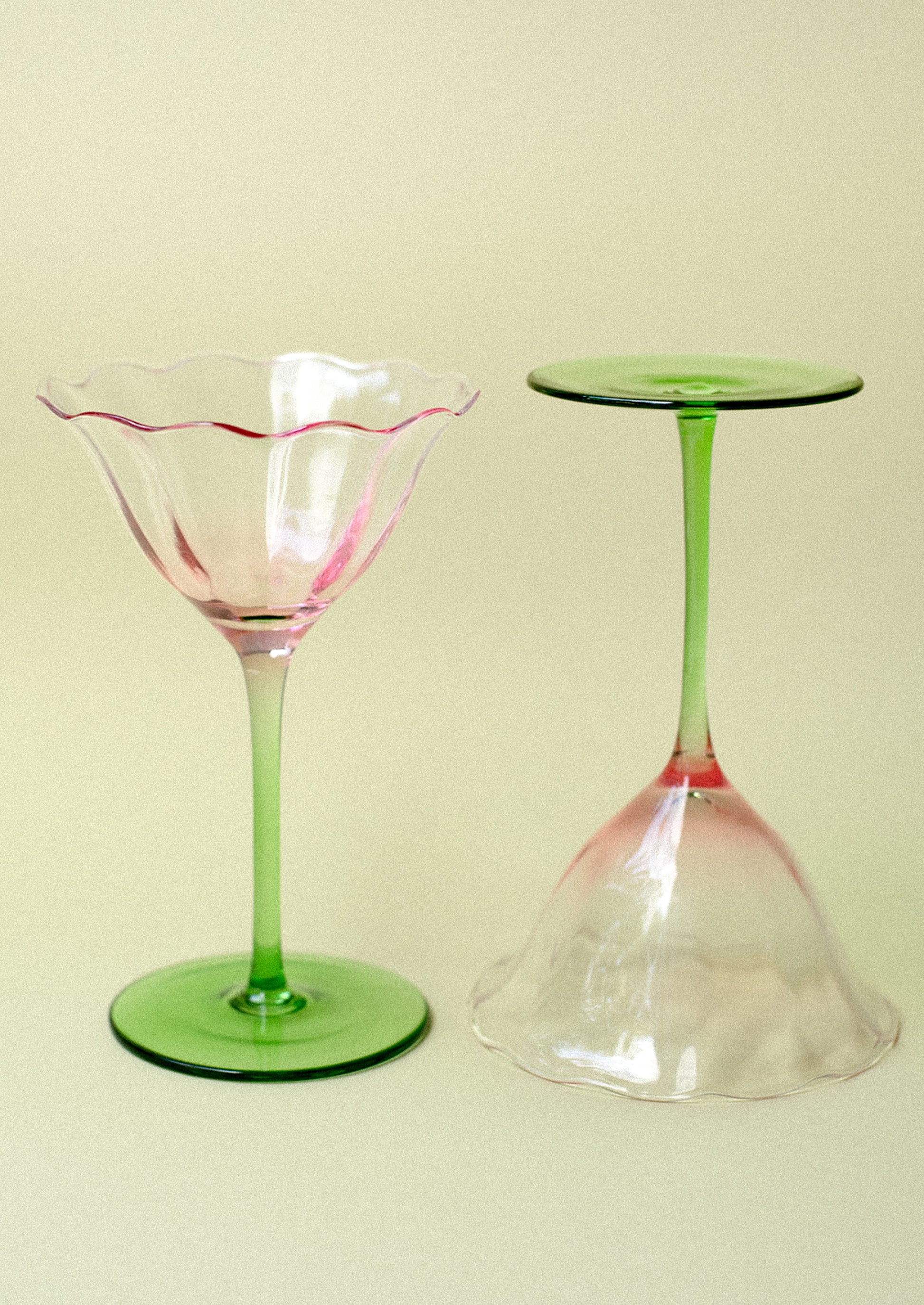 A coupe glass in shape of tulip with pink top and green bottom.