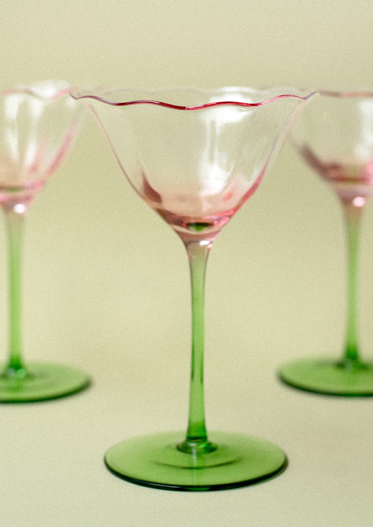 A coupe glass in shape of tulip with pink top and green bottom.