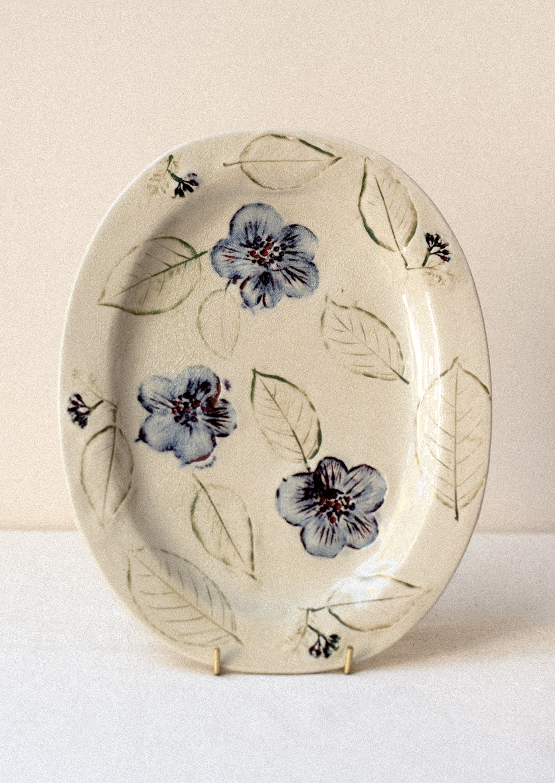 An ivory ceramic platter with blue pressed flower pattern.