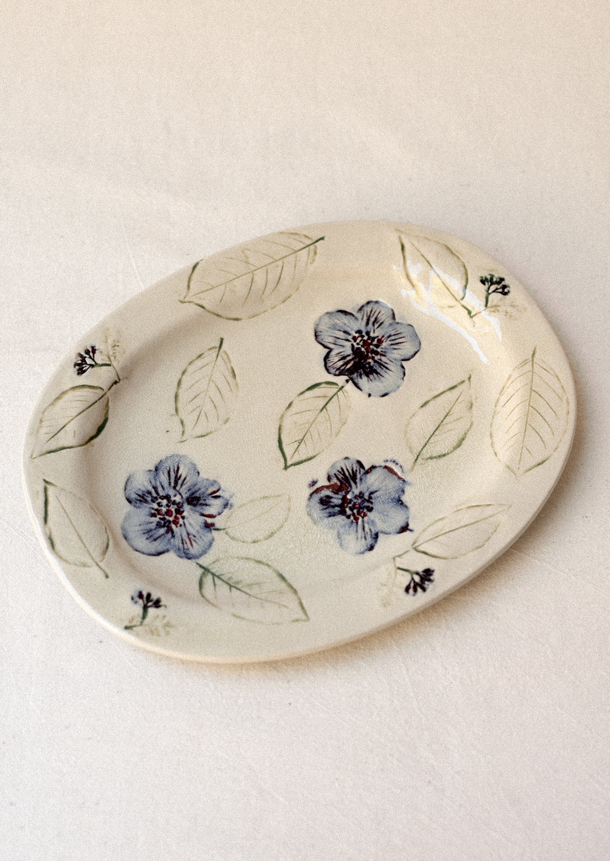 An ivory ceramic platter with blue pressed flower pattern.