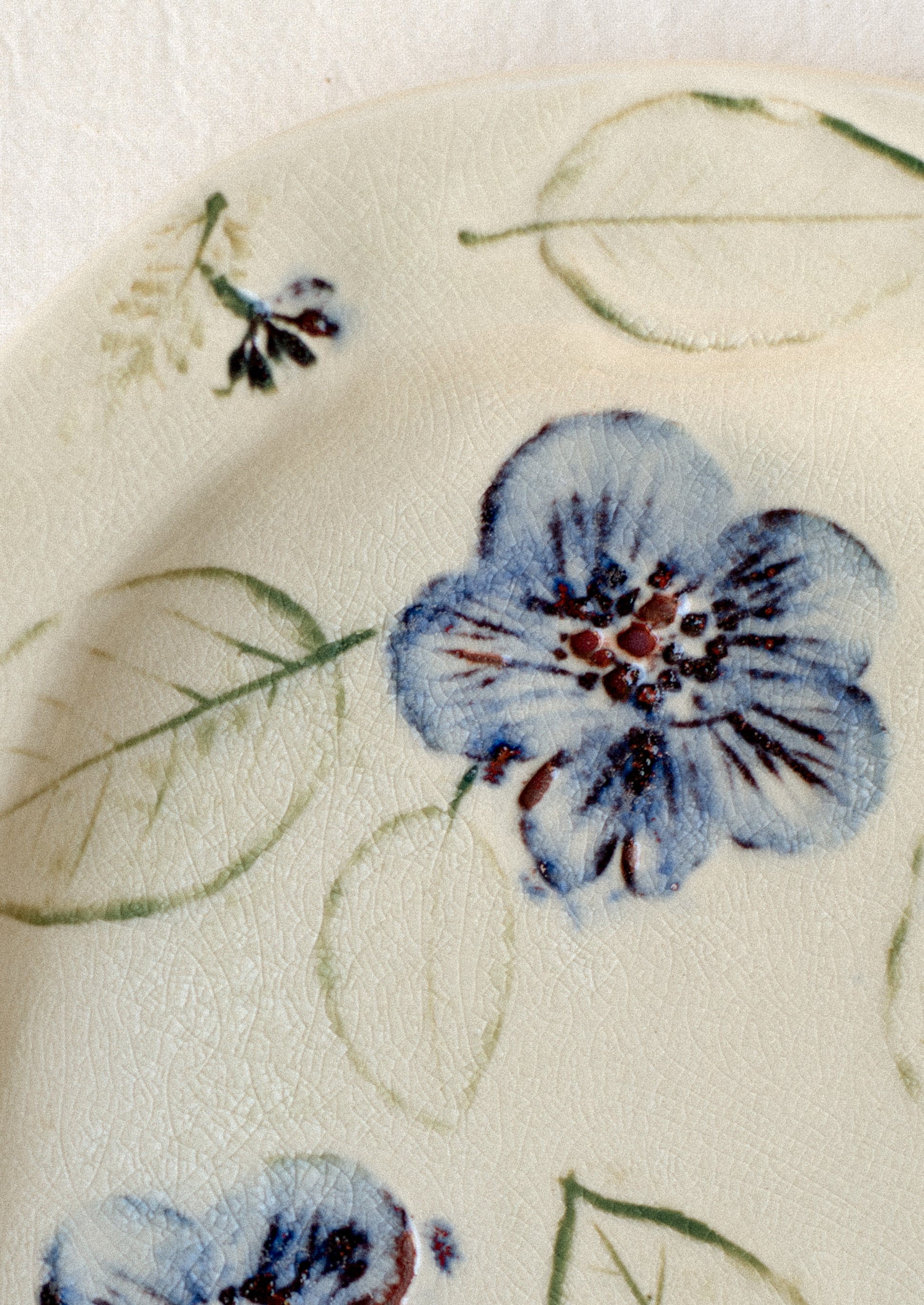 An ivory ceramic platter with blue pressed flower pattern.