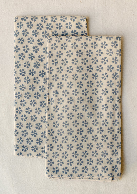 A pair of natural cotton-linen napkins with blue repeating floral pattern.