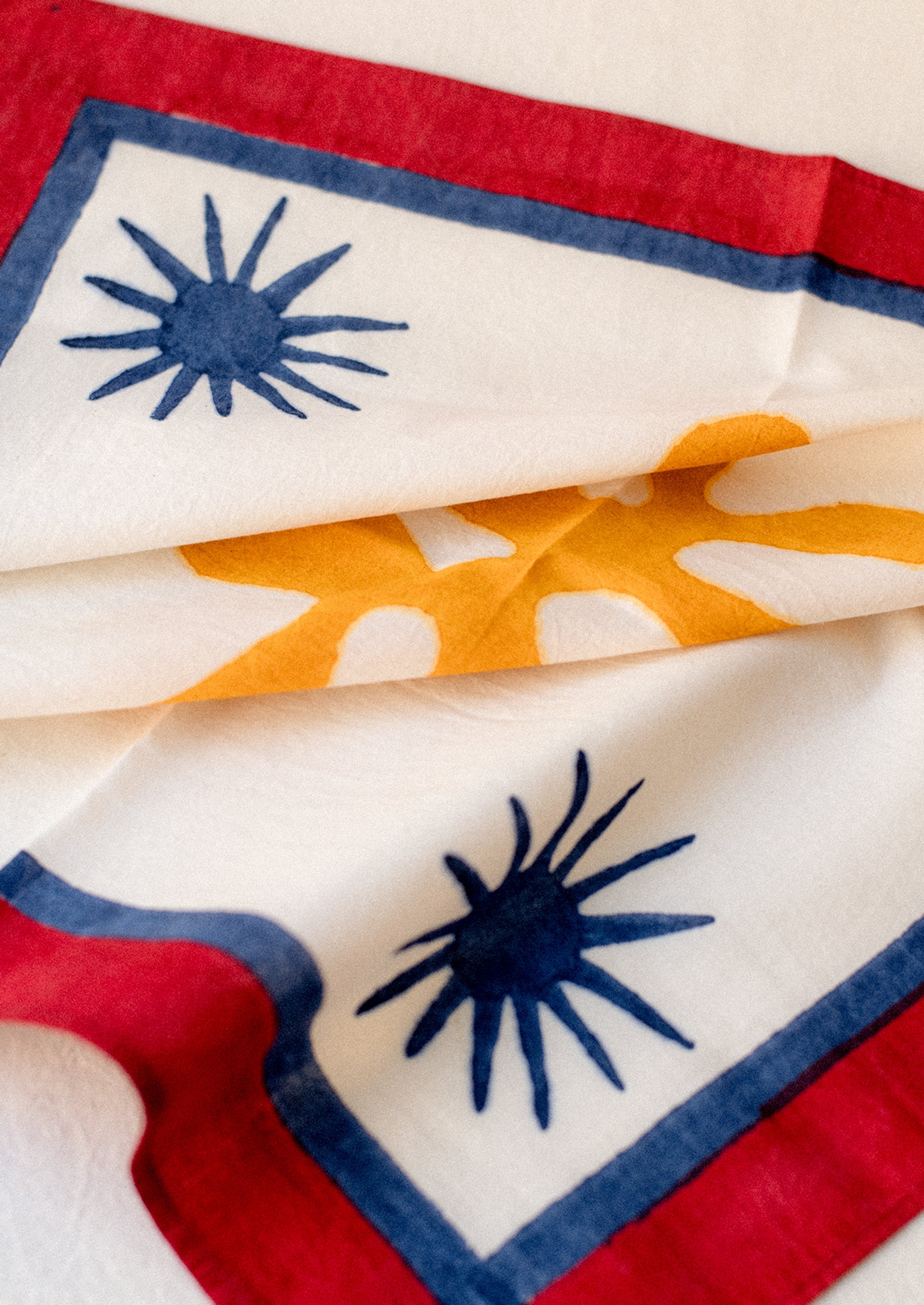 A block printed cotton napkin with Matisse-inspired star and leaf pattern in primary colors.