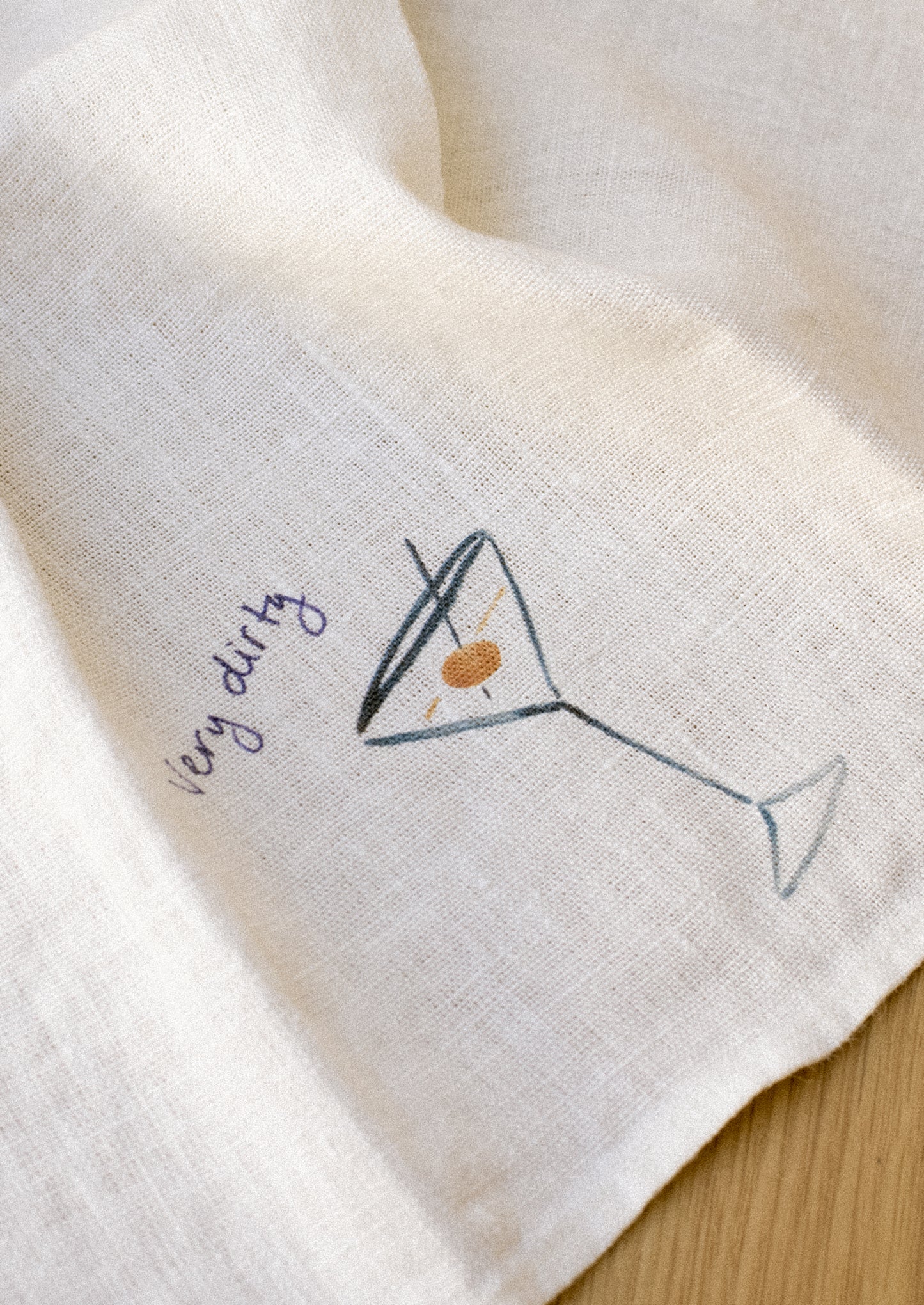 A white linen napkin with graphic detail of dirty martini.