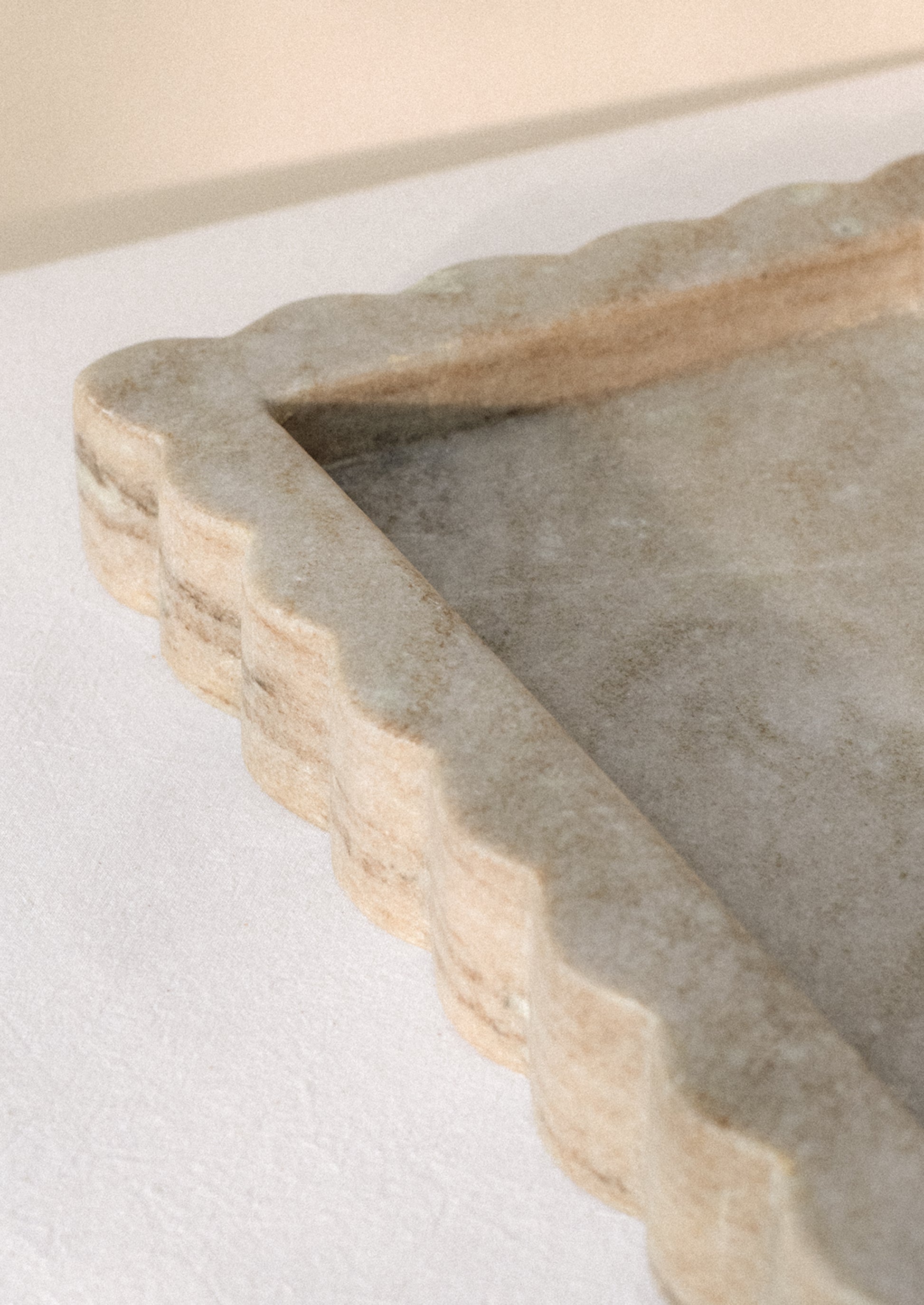 A rectangular tray in tan marble with inset center, raised scallop edge border.