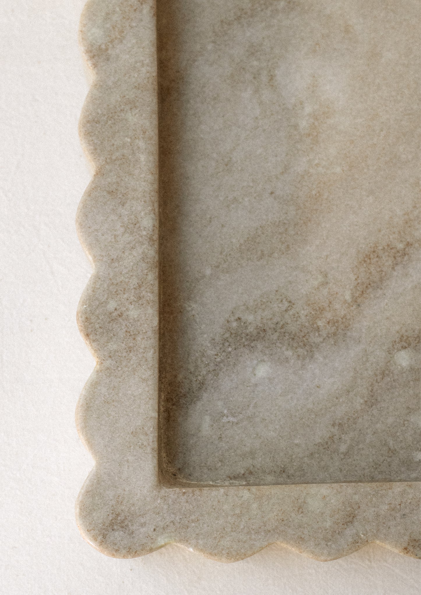 A rectangular tray in tan marble with inset center, raised scallop edge border.