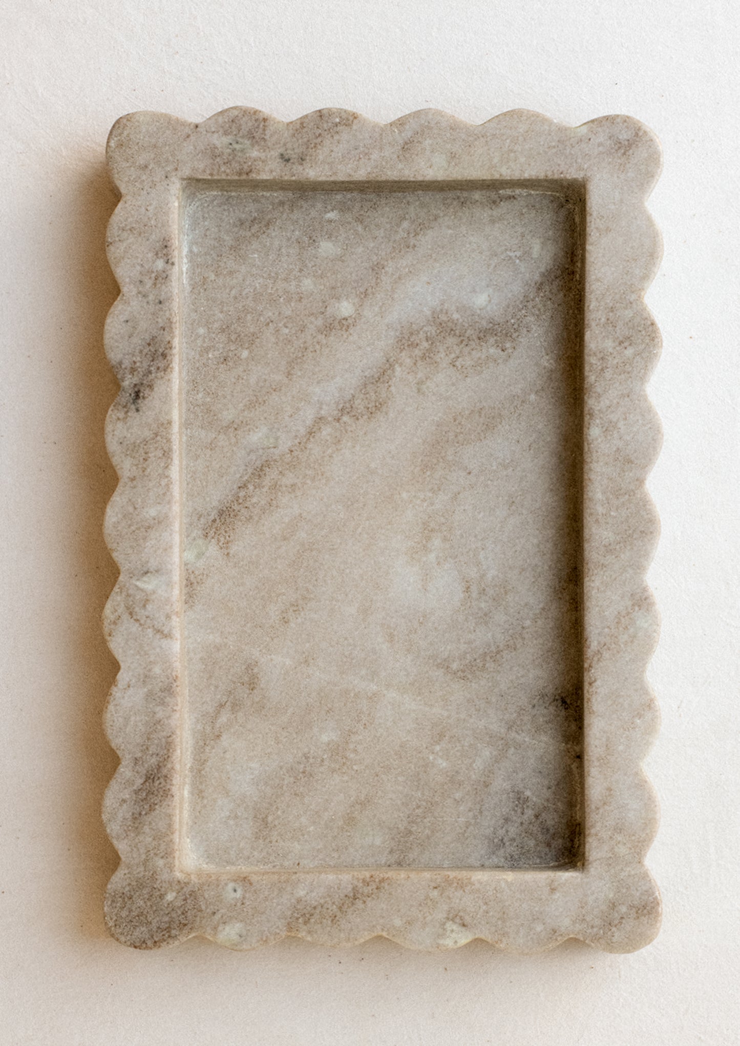 A rectangular tray in tan marble with inset center, raised scallop edge border.