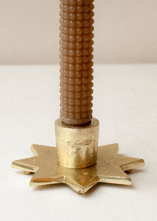 An eight-point star shaped taper candle holder in gold finish.