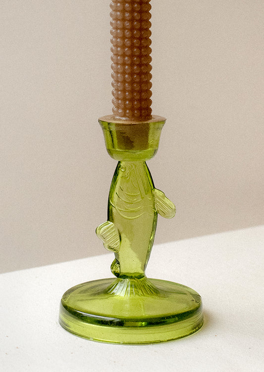 A green tinted translucent glass candle holder in the shape of a fish.