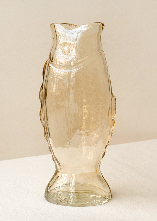 A transparent glass vase in the shape of a fish, in pale brown color with subtle iridescence.