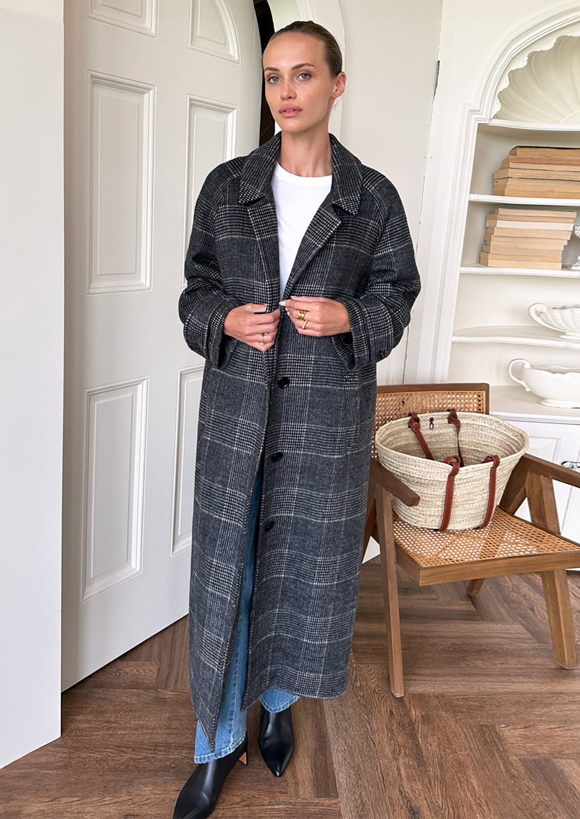 A woman wearing a long wool overcoat in charcoal and white plaid pattern.