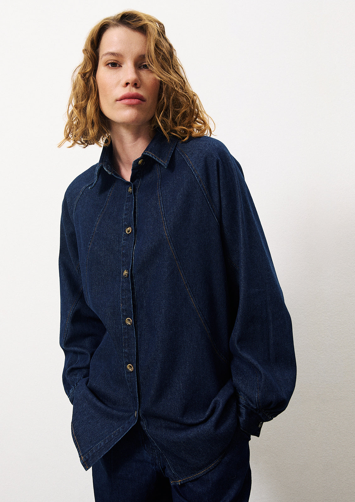 A woman wearing matching dark denim overshirt and jeans.