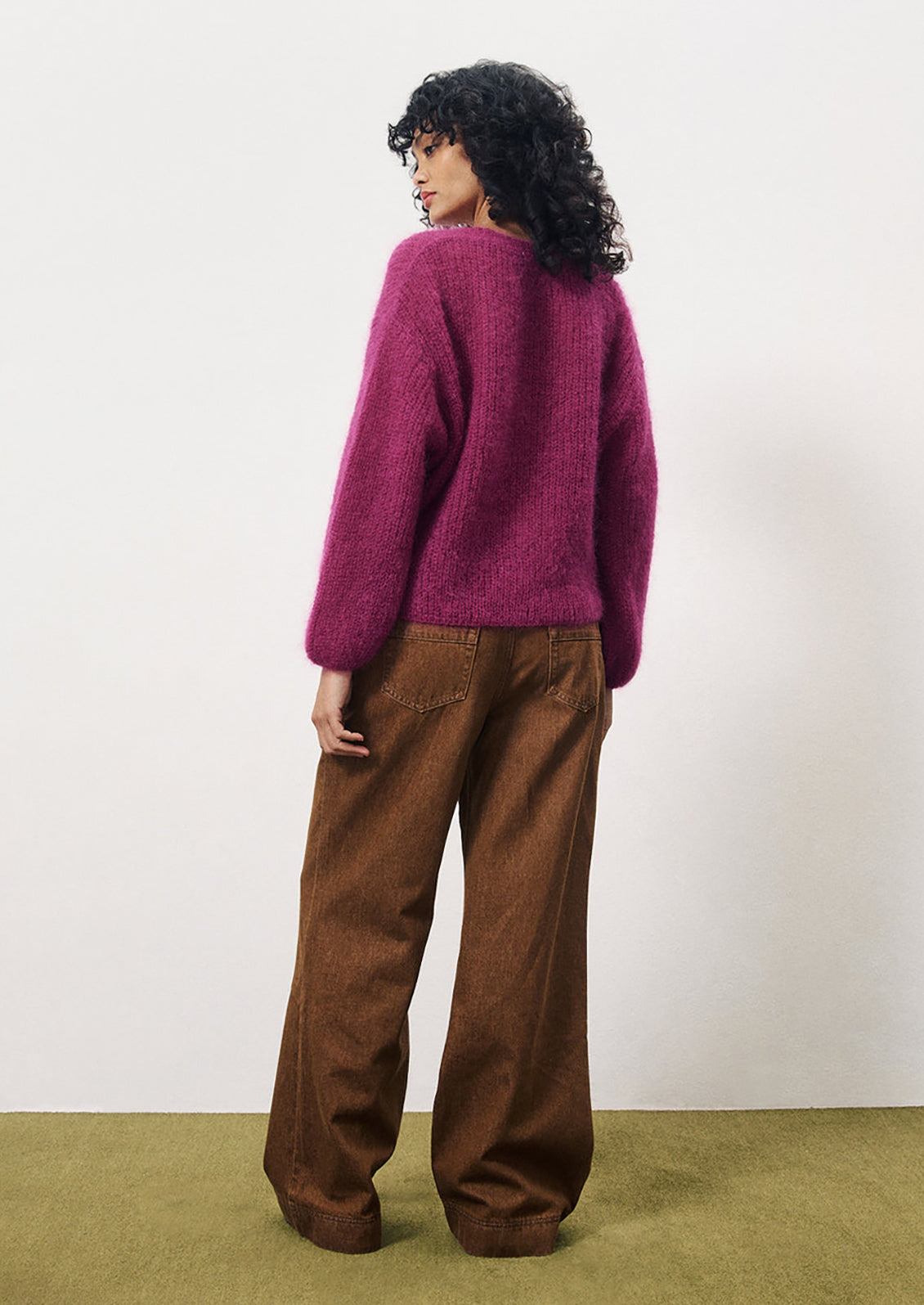 A woman wearing a vibrant magenta mohair v-neck cardigan.