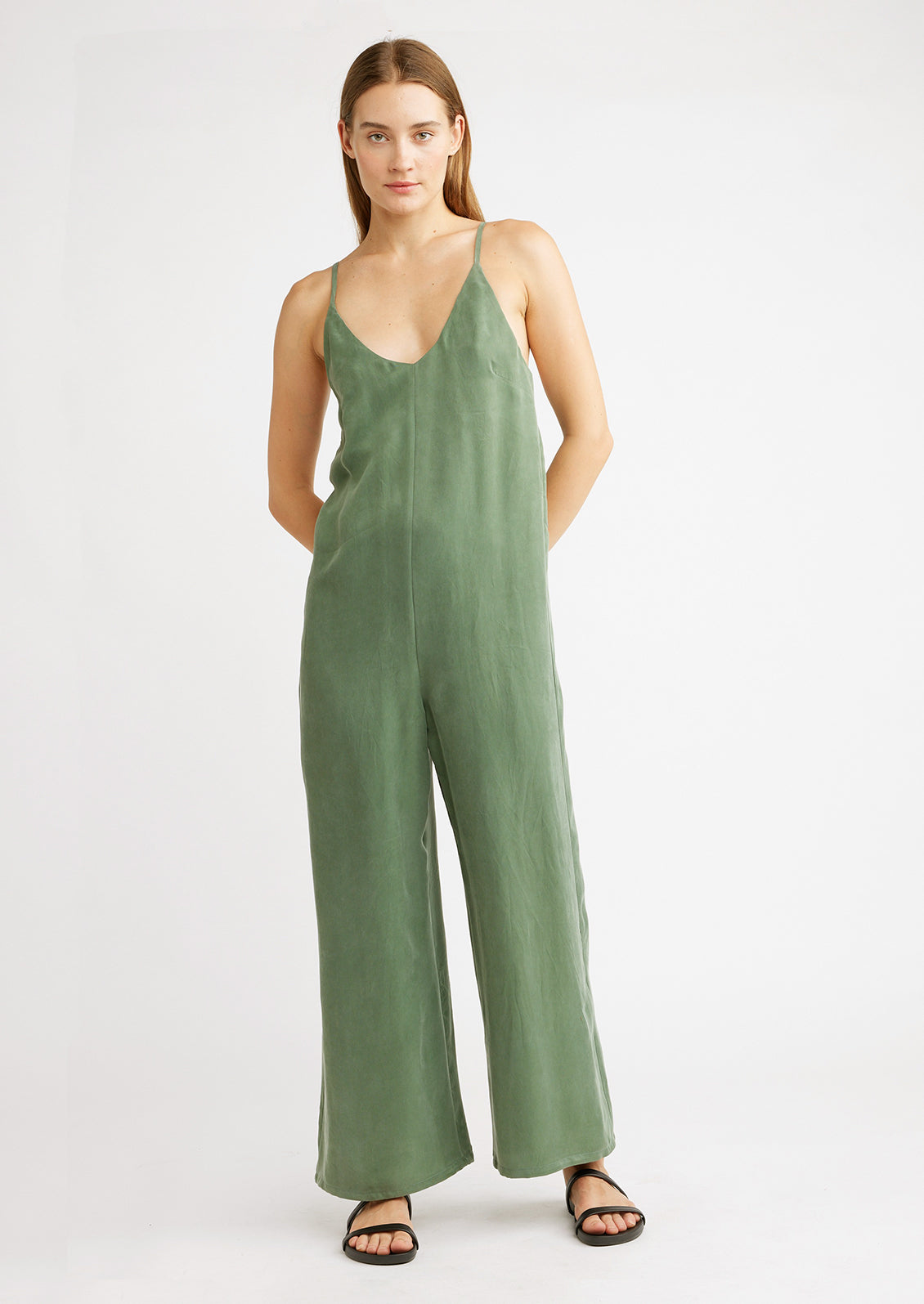 A woman wearing a green jumpsuit with black sandals