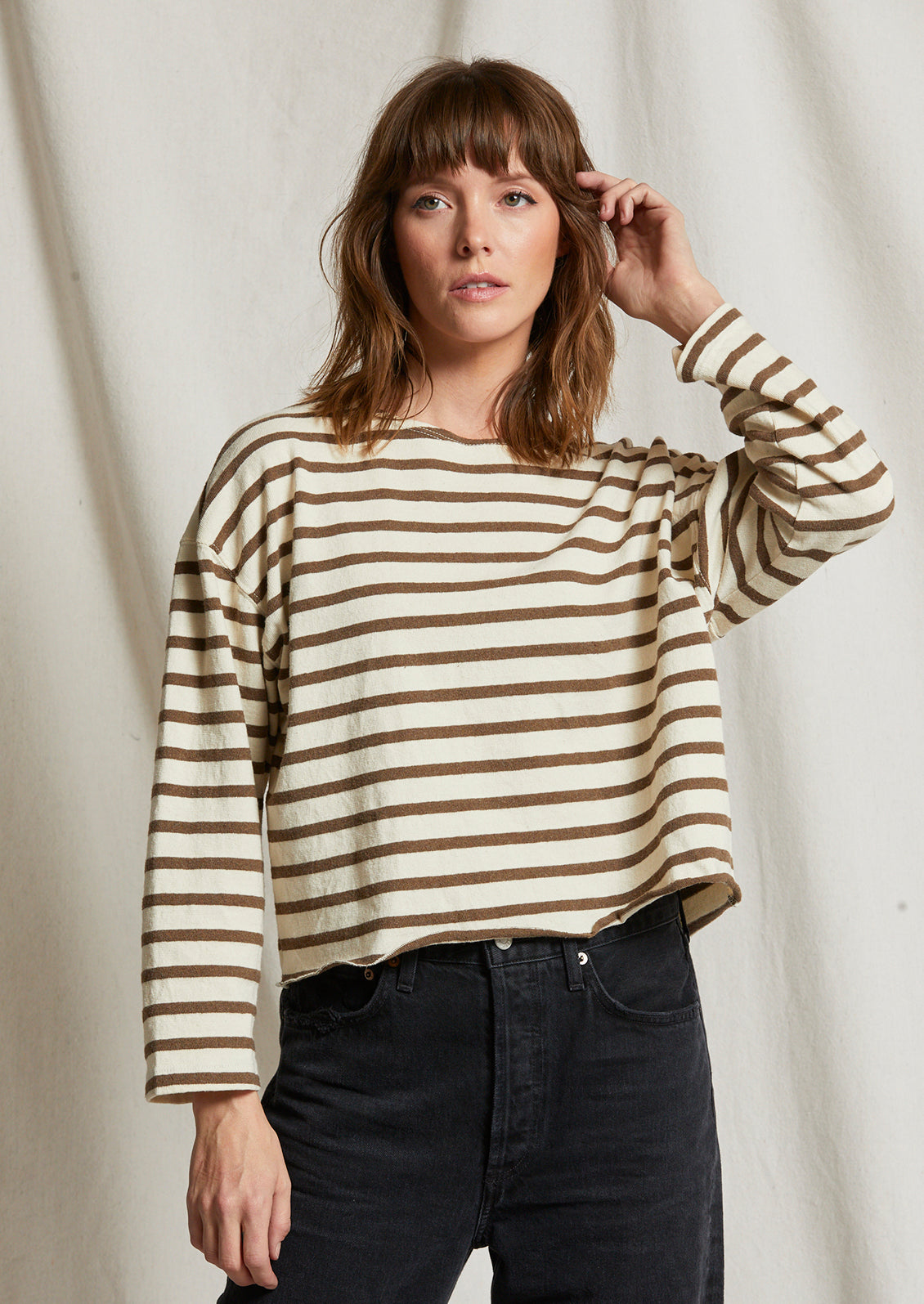 A woman wearing a long sleeve t-shirt in natural cotton with brown stripes.