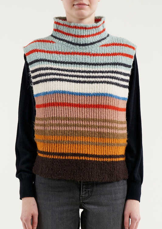 A person wearing a sleeveless turtleneck sweater in multicolor stripe.