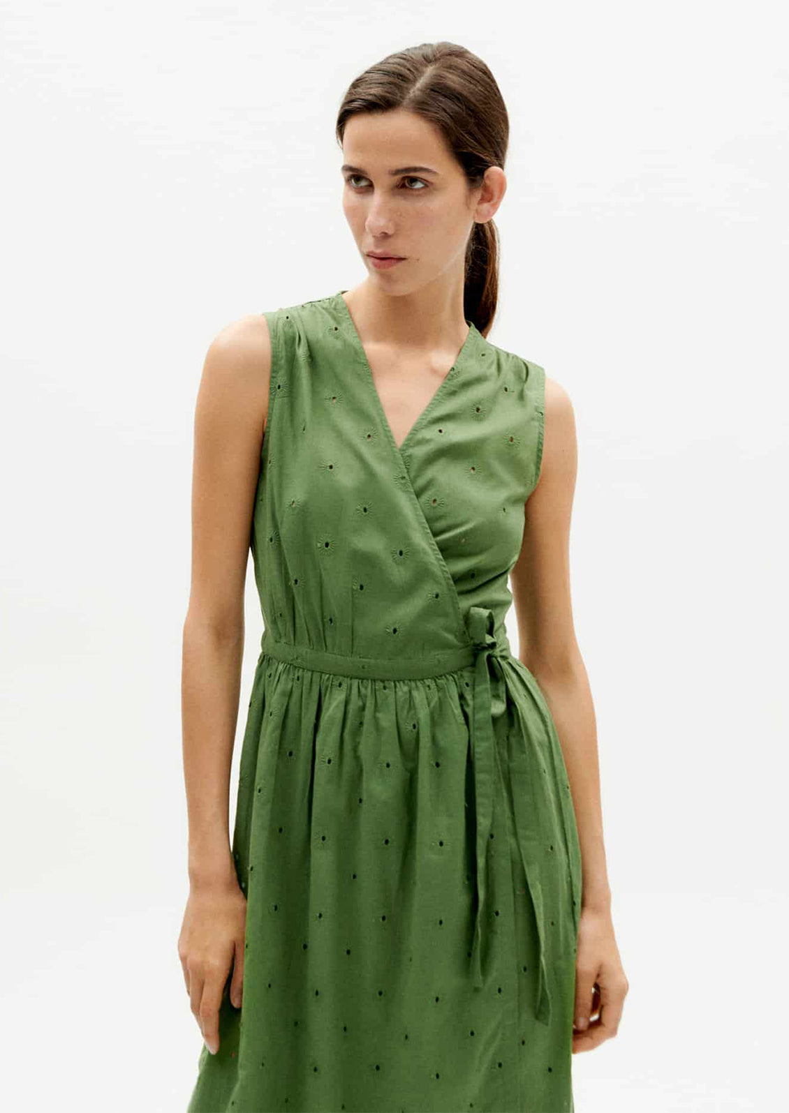 A woman wearing a green sleeveless midi wrap dress.