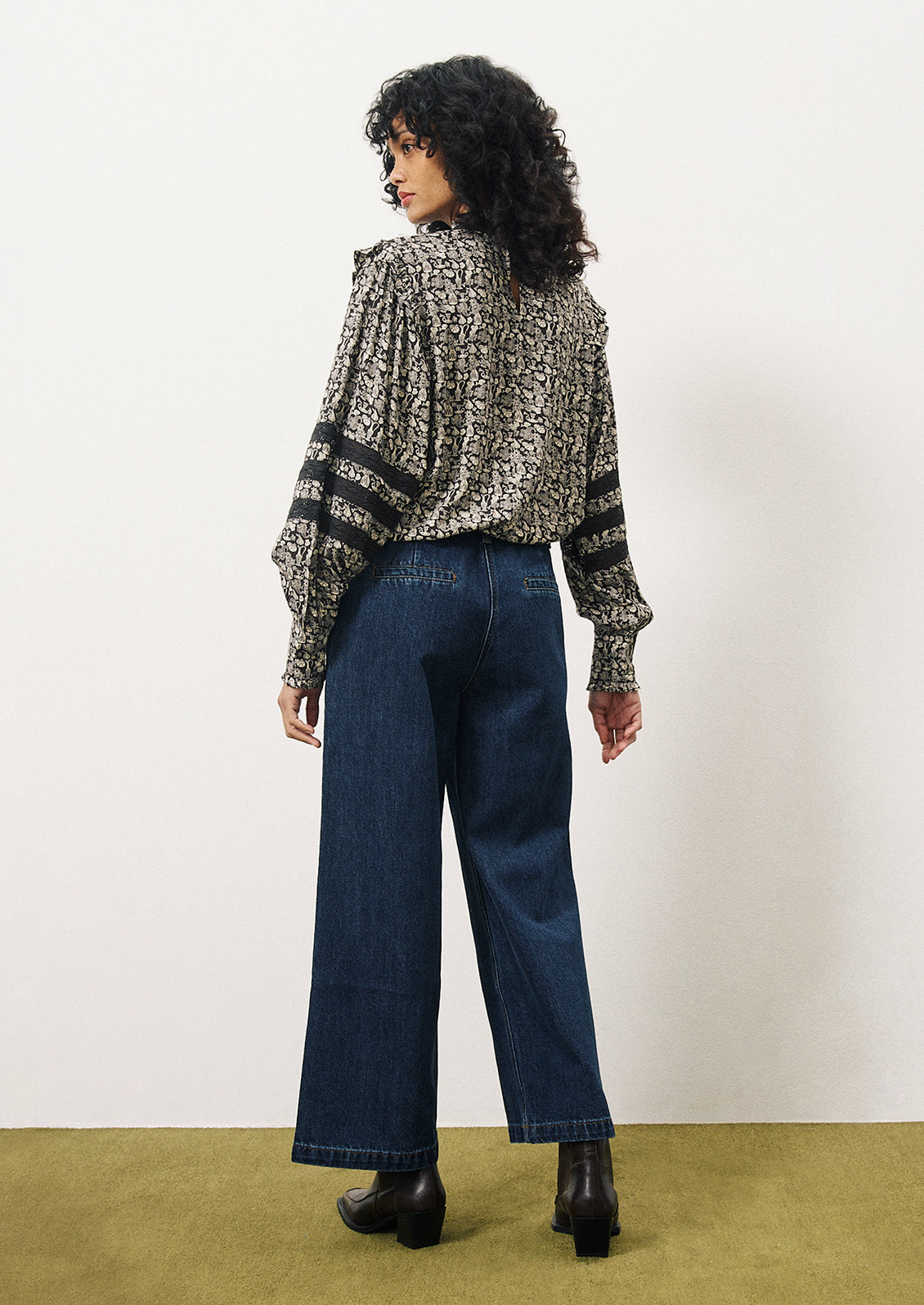 A woman wearing a printed blouse in dark blue with small white pattern of vases and flowers.