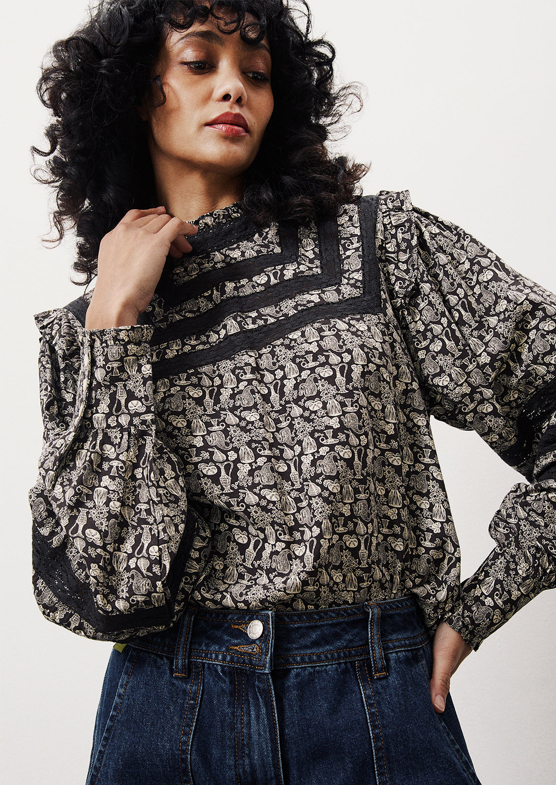 A woman wearing a printed blouse in dark blue with small white pattern of vases and flowers.