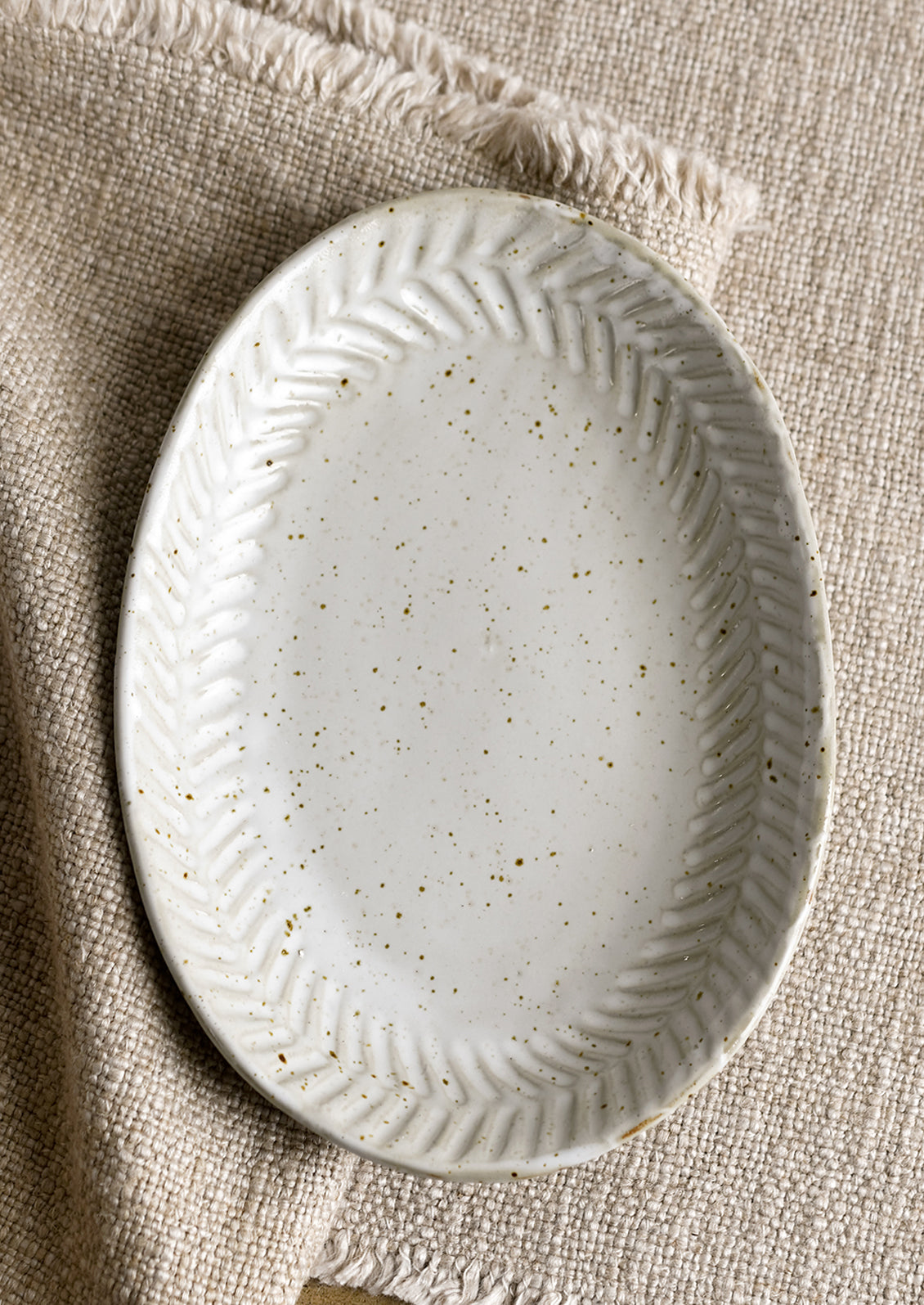 A ceramic tray in oval shape in speckled gray glaze.