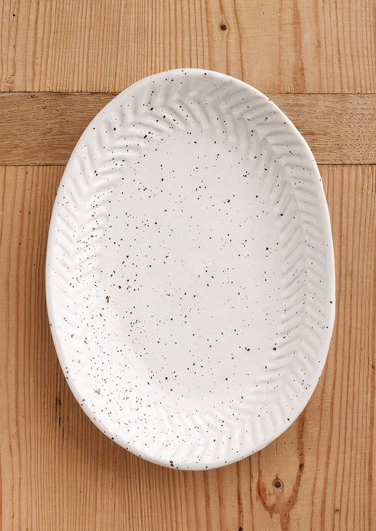 A ceramic tray in oval shape in speckled bright white glaze.