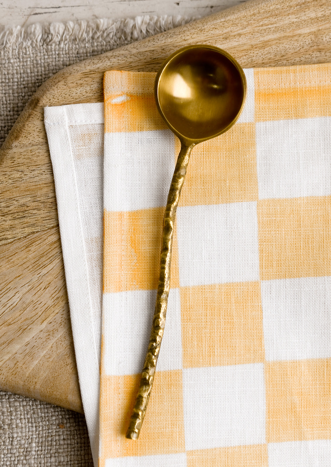 A brass spoon with textured organic shaped handle.