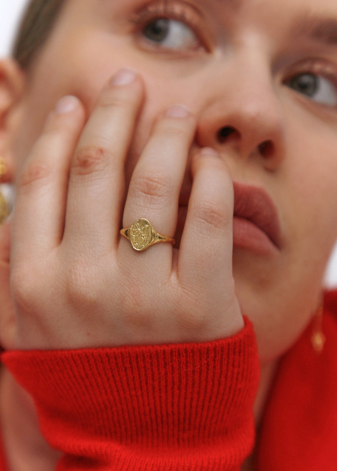 A woman wearing a gold signet ring with etching of a bow.