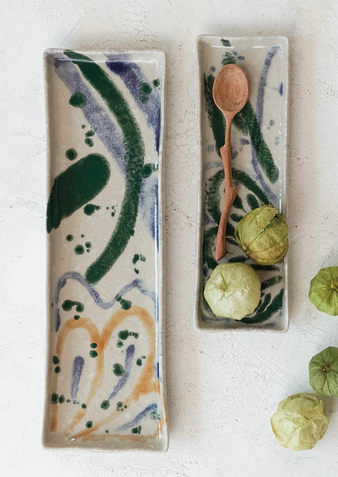 Long rectangular ceramic trays with multicolor paint splatter pattern.