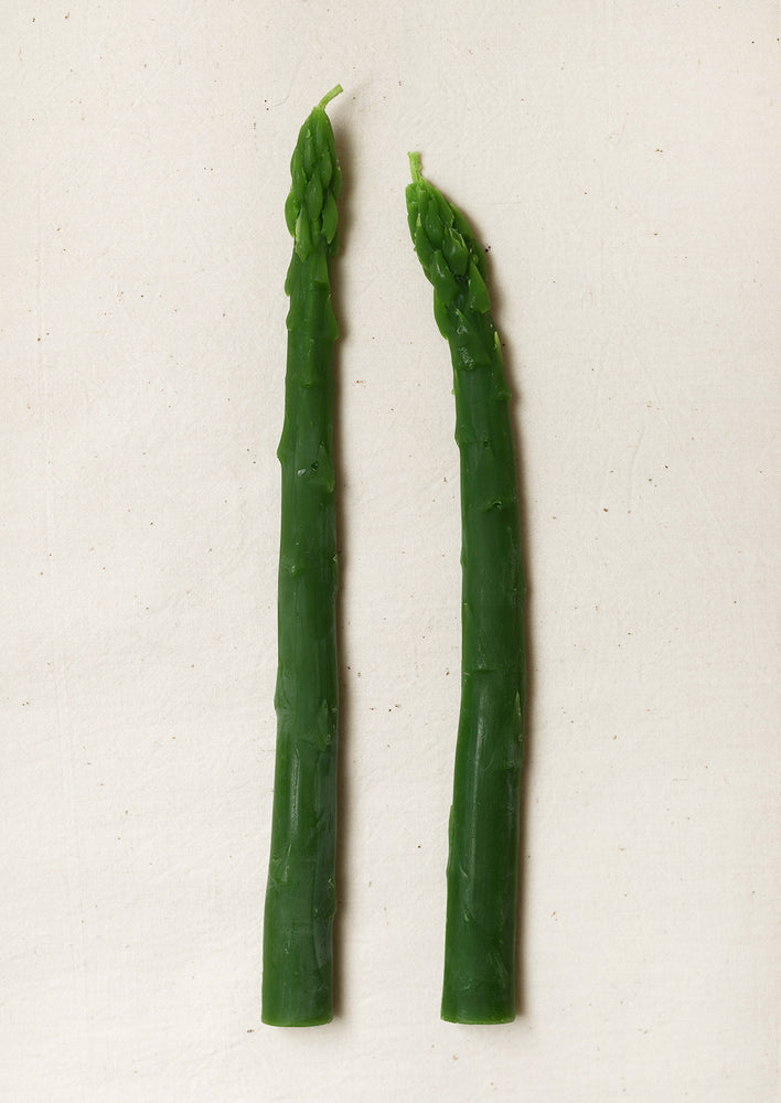 A pair of green beeswax taper candles in a realistic asparagus shape.