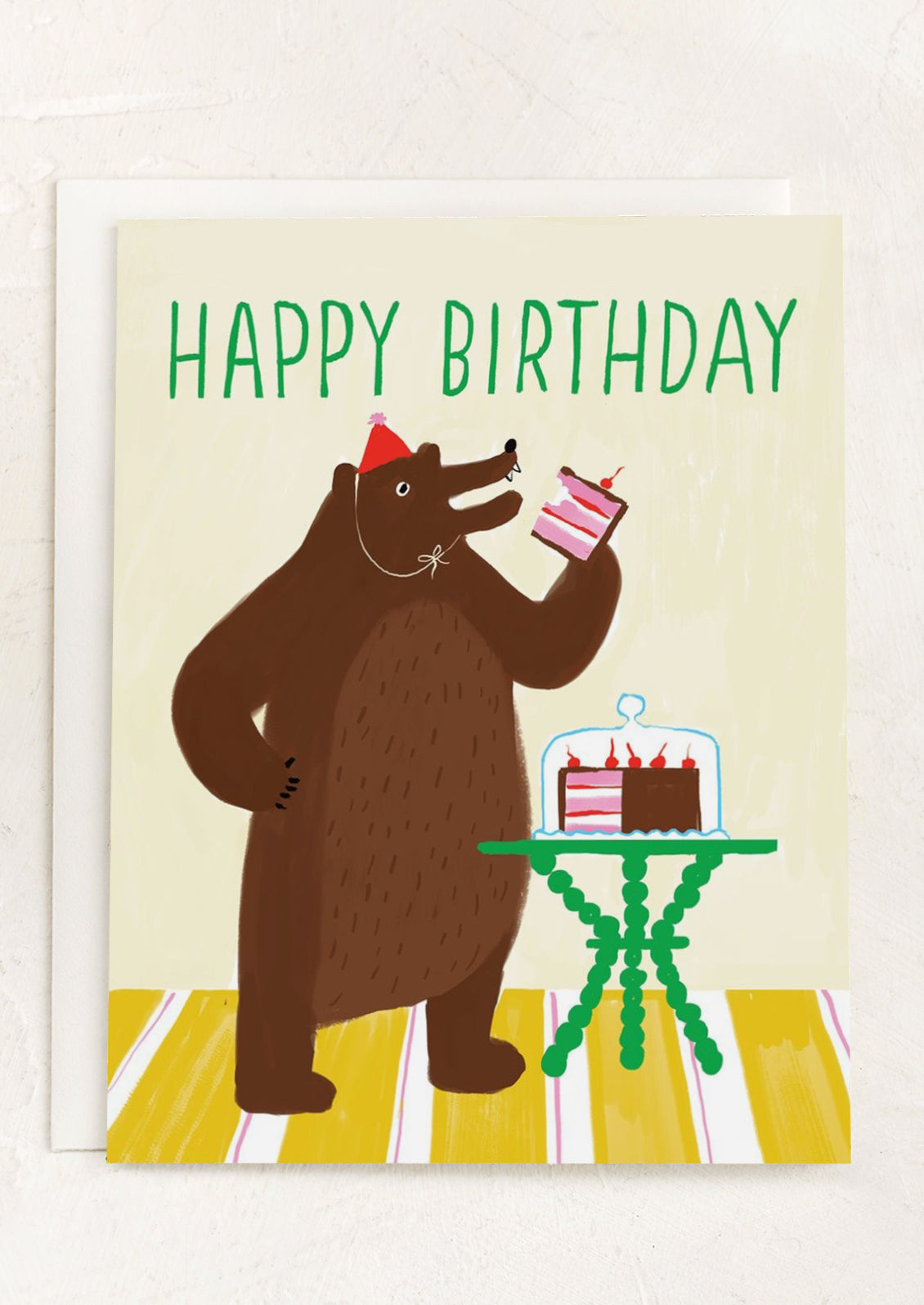 A greeting card with illustration of a bear eating cake, text reads "Happy Birthday".