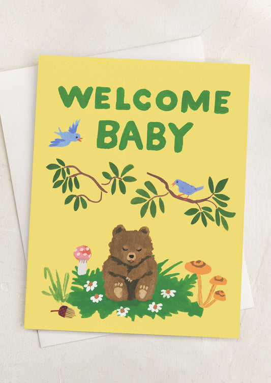 A greeting card with image of bear cub, text reads "Welcome Baby".