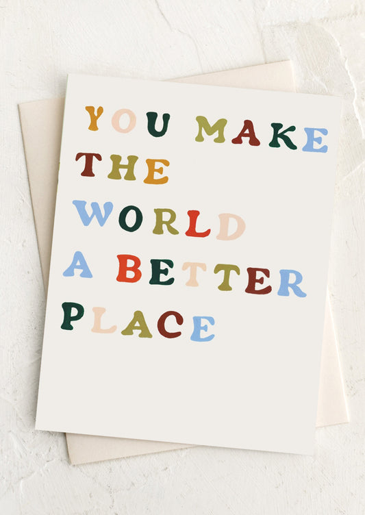 White notecard with rainbow painted text "You Make The World A Better Place Card" with blush envelope.