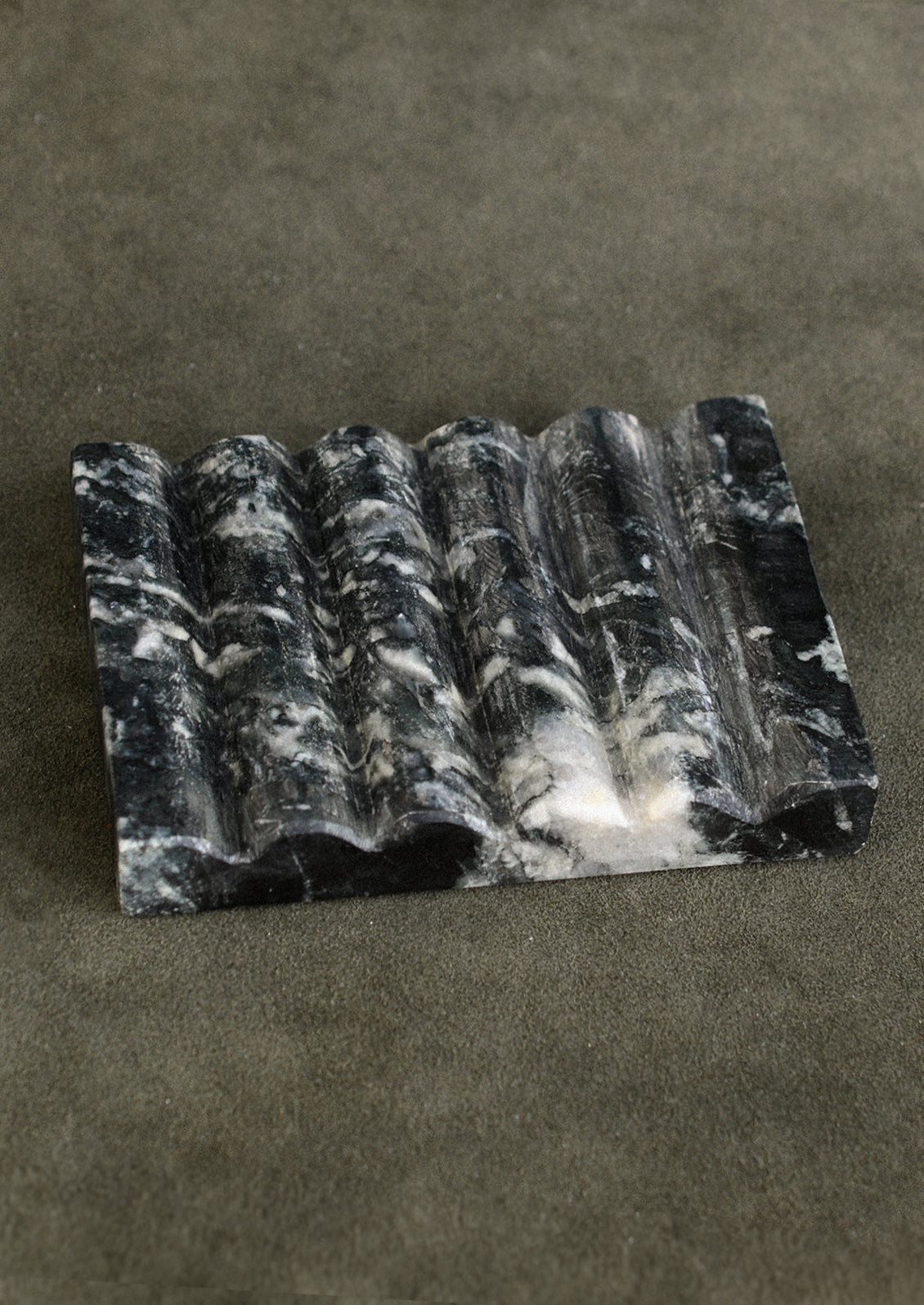 A fluted marble soap dish in black marble with white veining.