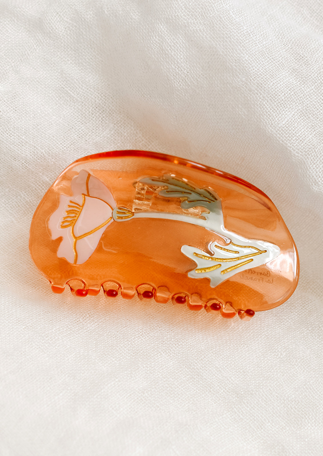 A peach curved shape hair claw with tulip design.