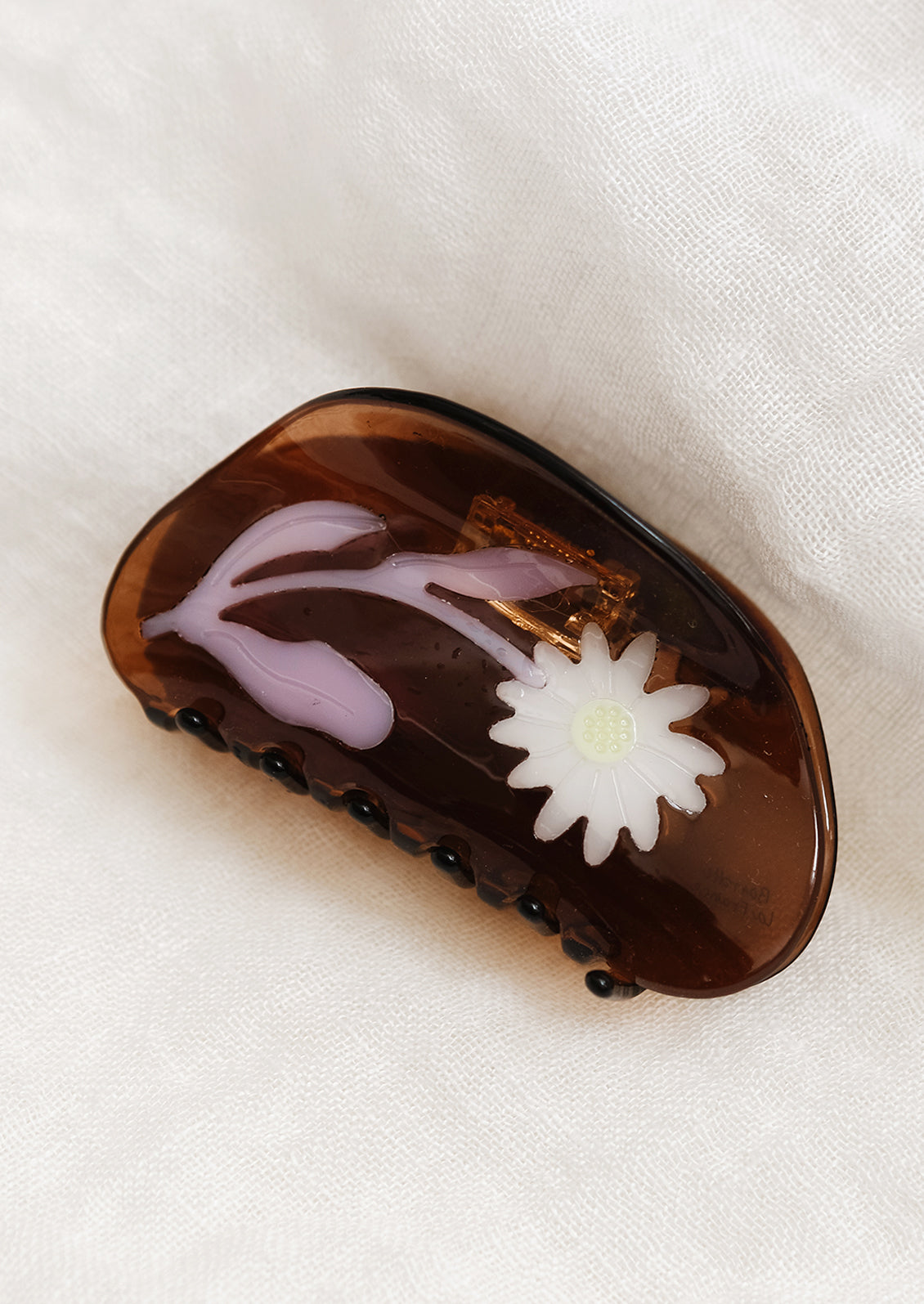 A brown curved shape hair claw with white and purple sunflower.