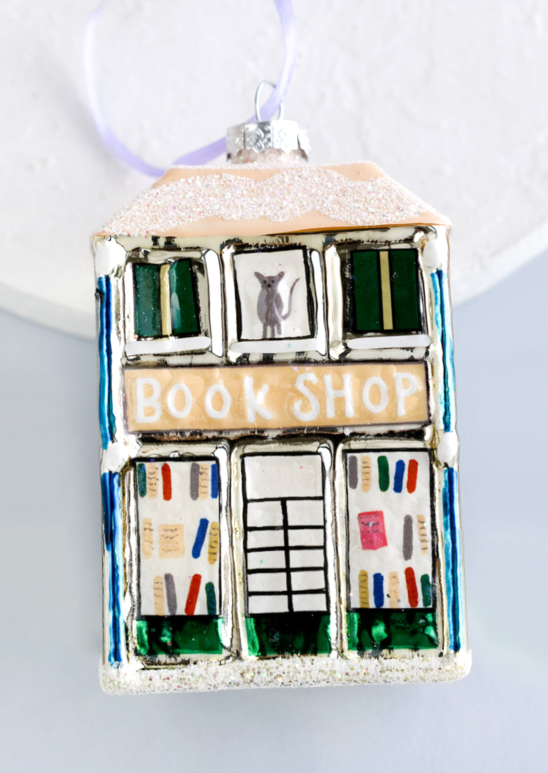 A glass holiday ornament of a book shop building.