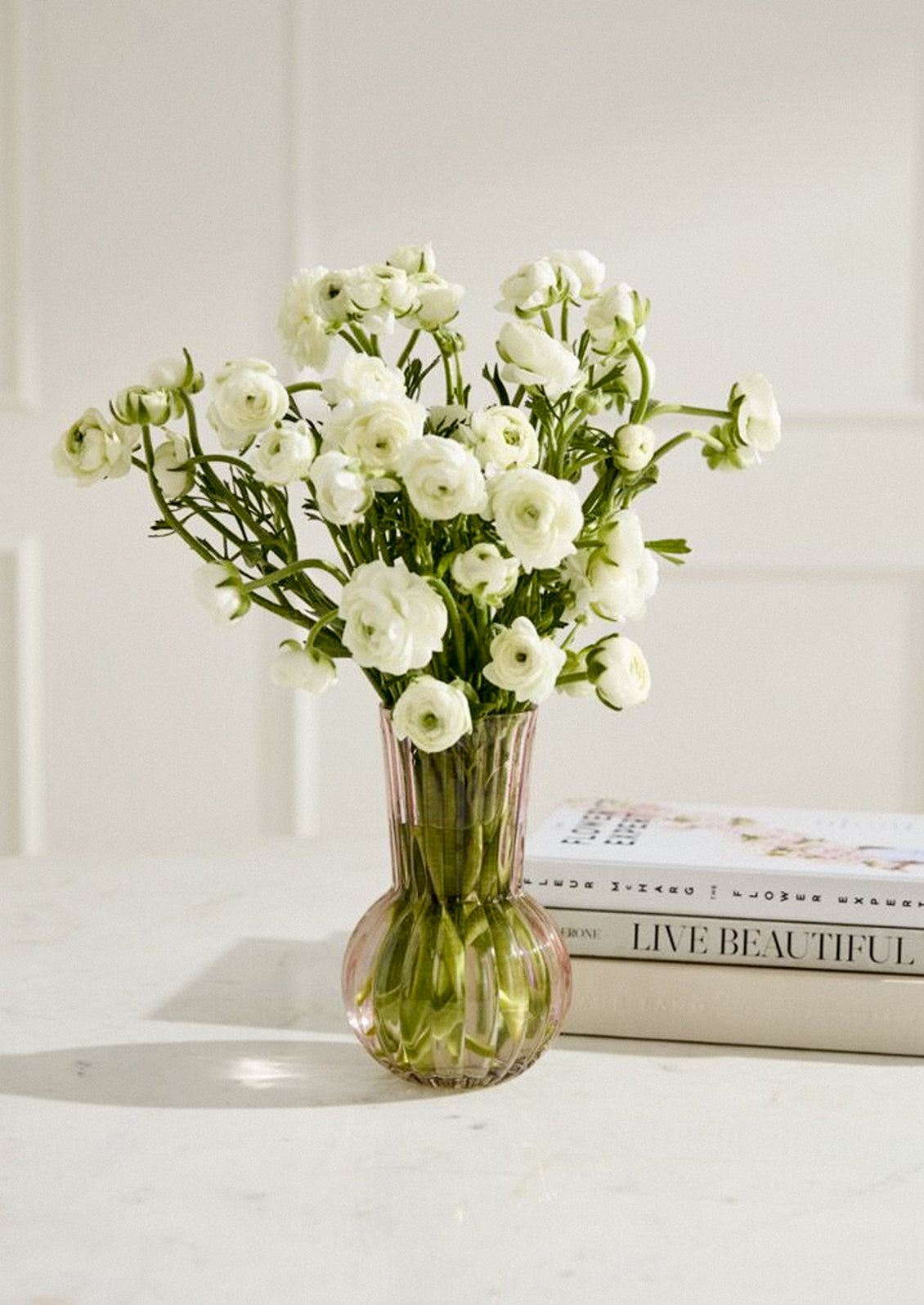 A glass vase in fluted light pink glass with bulb-like shape.