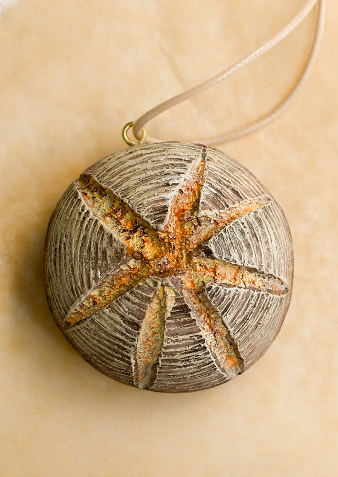 A holiday ornament in shape of scored round bread loaf.