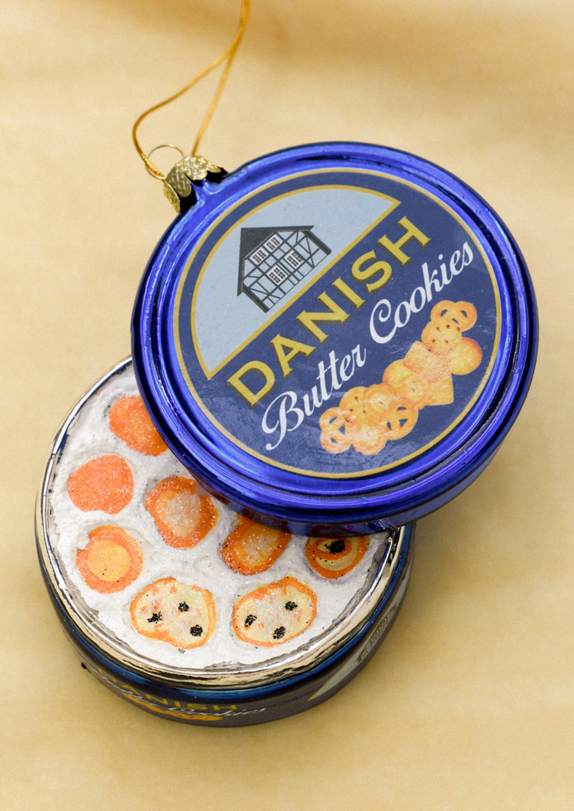 A glass ornament depicting an open blue tin of Danish butter cookies.