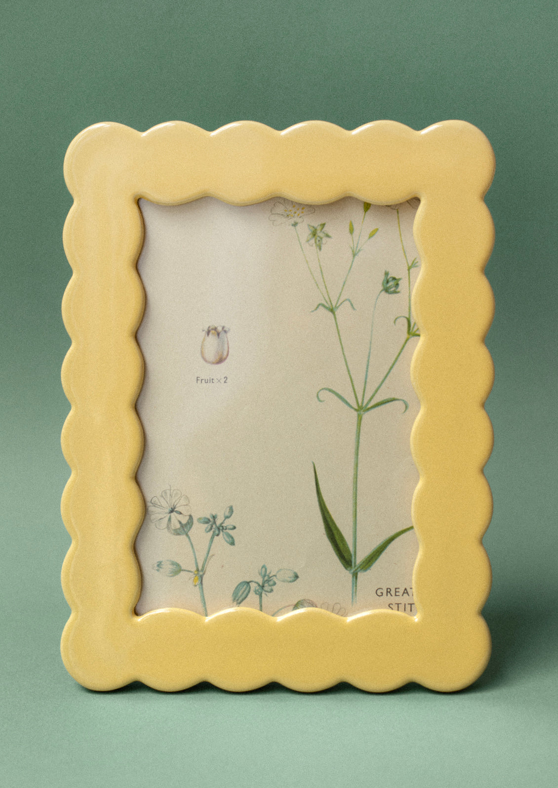 A rectangular picture frame in wavy squiggle shape in butter yellow ceramic.