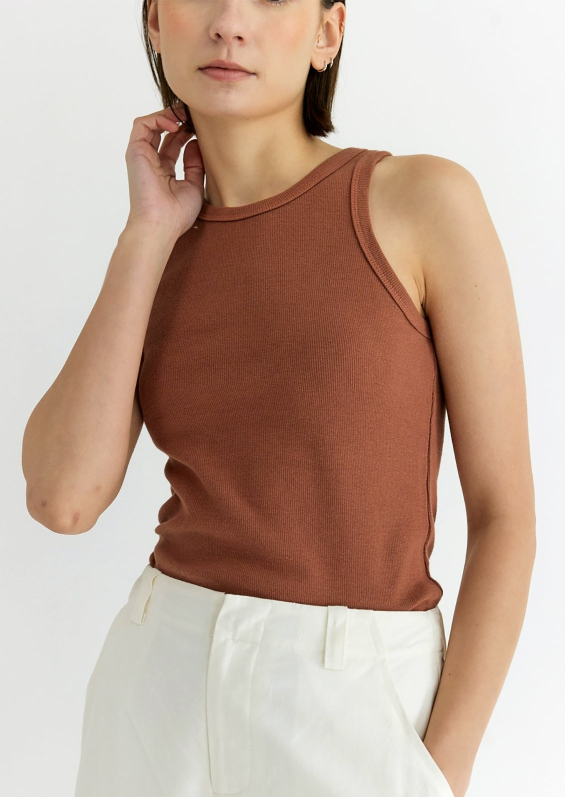A woman wearing a rust colored ribbed tank top.