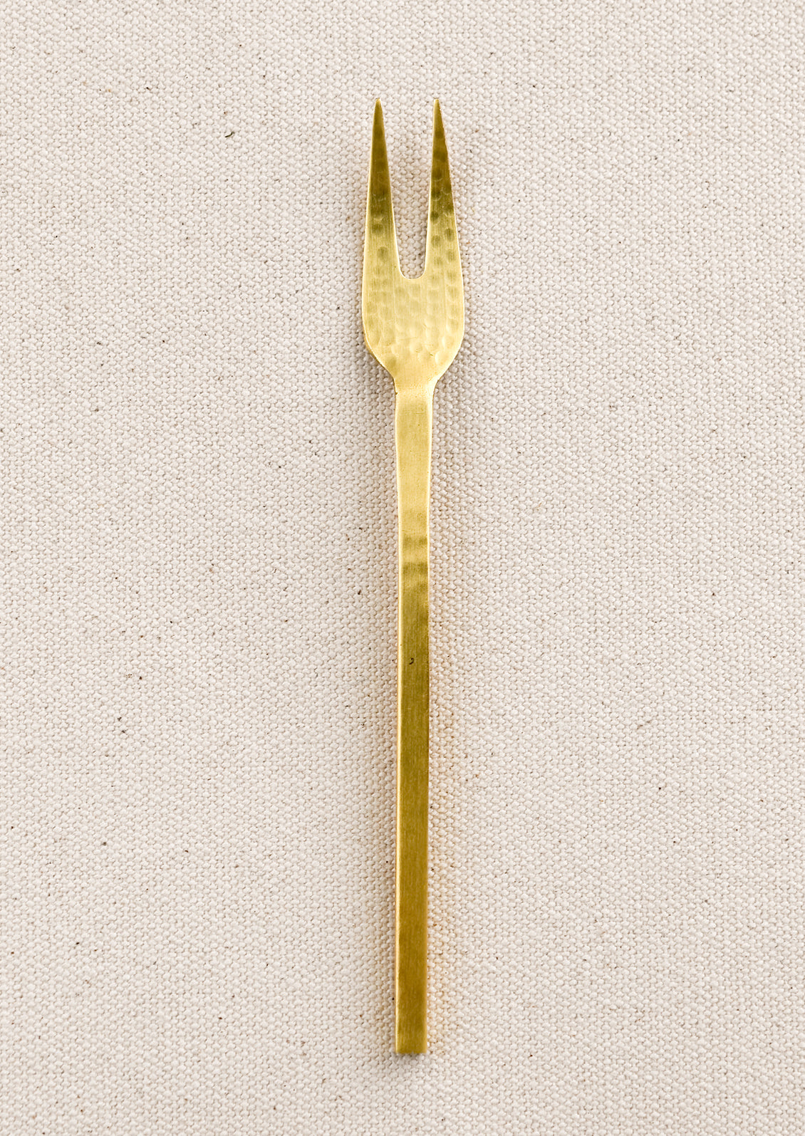 A small canape fork in hammered gold finish.